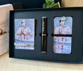 Load image into Gallery viewer, A gift set in a black box featuring notepad holder and matching bookmark with flamingo illustrations and a black pen with silver trim. A branded box is partially visible on the left.