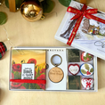 Load image into Gallery viewer, A Christmas-themed gift box set from Krevana, featuring a poppy sticky notepad with the quote 'Your own limit is your mindi, a round wooden keychain engraved 'You are Best Ever', and six small chocolates with festive designs. The gift box is styled on a light wooden surface with a gold ornament, green leaves, and a plaid ribbon.
