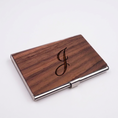 Load image into Gallery viewer, A rectangular business card case with a dark brown wood grain finish and a polished silver metal clasp, featuring a black engraved script letter 'J' on the front, set against a plain light gray background.
